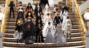 Bride Vanessa Blaylock, Groom Ze Moo, and their wedding party stand on the staircase of the Grand Ballroom, Covent Garden, London. The women are all dressed in white and the men are all dressed in black.