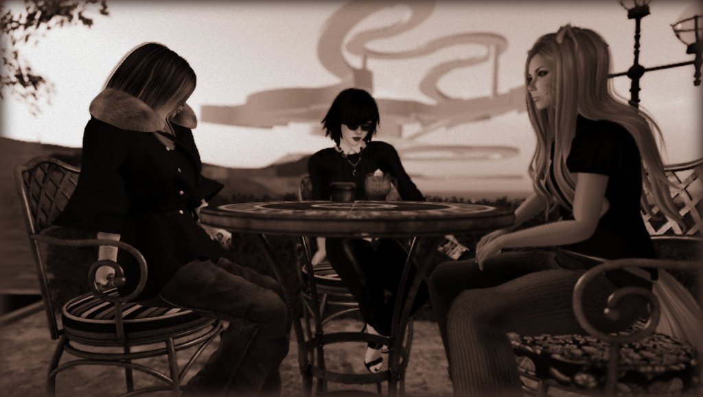 Scarlett Luv-Star, Vanessa Blaylock, and Emma Maybe sit at a tile-topped table on a terrace having coffee on a dusky morning