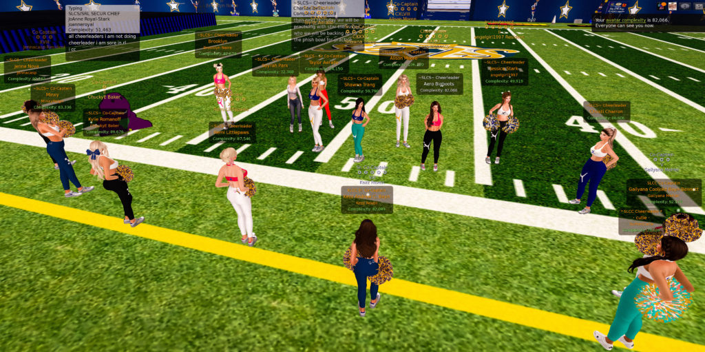 Members of the Second Life Cheerleading squad stand on the sideline of a football stadium as announcements are shared. 